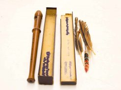 Vintage wood wind instrument with accessories, including boxes and decorative feathers for musical nostalgia.