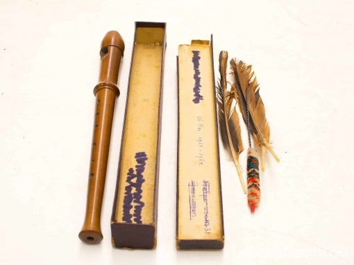 Vintage wood wind instrument with accessories, including boxes and decorative feathers for musical nostalgia.