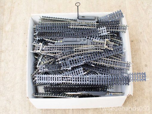 Used model train tracks and components in a worn white box for hobbyists creativity.