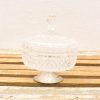Elegant crystal jar with lid, featuring intricate patterns and rustic wooden backdrop.