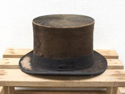 Aged vintage top hat on wooden surface, showcasing timeless elegance and rustic charm.