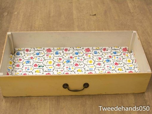 Charming vintage yellow drawer with floral lining and brass handle for stylish storage.