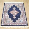 Deep navy vintage rug with floral motifs, elegant medallion, and soft fringes for stylish decor.