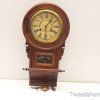 Elegant antique regulator clock with polished wood, Roman numerals, and intricate carvings.
