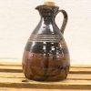 Elegant ceramic jug with cork stopper, showcasing artisanal craftsmanship and earthy tones.