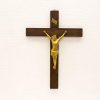 Golden Jesus crucifix on a dark wooden cross, symbolizing sacrifice and reverence.