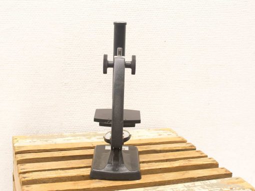 Vintage black microscope on wooden surface, showcasing exquisite craftsmanship and timeless design.