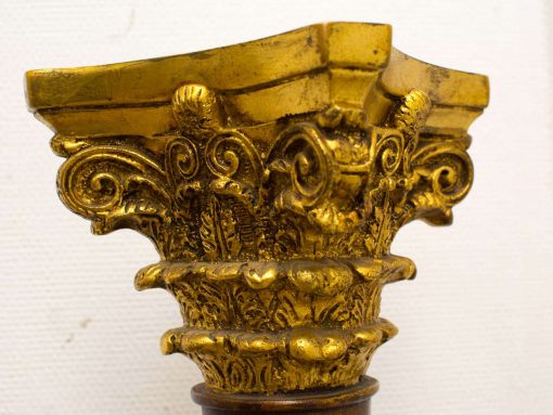 Elegant golden Corinthian column capital showcasing intricate scroll and floral designs.