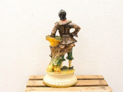 Vintage figurine of a confident man with a basket, showcasing intricate details and charming style.