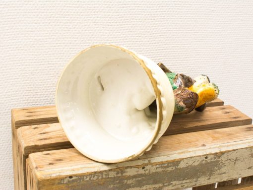 Elegant overturned ceramic vase with colorful designs on a rustic wooden surface.