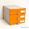 Modern orange filing cabinet with three drawers and a sleek gray top for office organization.