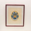 Elegant maroon-framed coat of arms artwork in blue and gold, showcasing heraldic artistry.