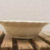 Elegant beige ceramic bowl with scalloped edge, perfect for serving salads or desserts.