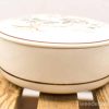 Elegant cream ceramic container with hand-painted floral design for decoration or storage.