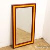 Stylish mirror with deep maroon and sunny yellow frame, perfect for any living space.