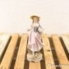Charming vintage figurine of a woman in pink dress holding a flower basket.
