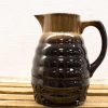 Elegant handmade brown and black ceramic pitcher with unique ridged texture and glossy finish.