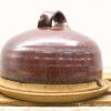 Handmade ceramic cloche with rich reddish-brown glaze, perfect for serving and decoration.