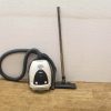 Modern white canister vacuum cleaner with flexible hose, ideal for versatile home cleaning tasks.