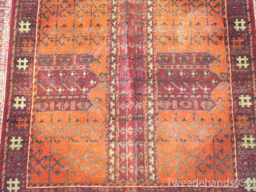 Intricate vintage orange rug with geometric and floral patterns, showcasing traditional craftsmanship.