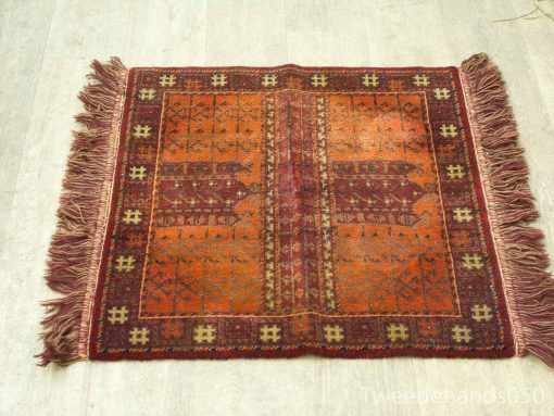 Handwoven vintage rug with warm geometric patterns in red, orange, and brown tones.
