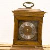 Elegant vintage wooden table clock with intricate details and Roman numeral dial.