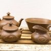 Charming vintage brown ceramic teapots, creamer, and bowl for a cozy kitchen atmosphere.
