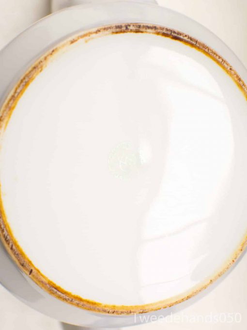 Vintage white ceramic mug with brown rim, perfect for warm beverages and home decor.