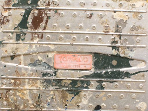 Vintage Tomado metal step ladder with unique patina and textured surface.