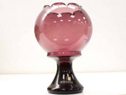 Elegant translucent pink glass bowl with scalloped edges on a sleek black pedestal.