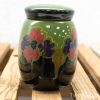 Vibrant green ceramic jar with floral patterns and a glossy black lid, perfect for decor.