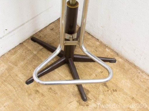 Adjustable industrial stool with shiny metal legs and deep brown wooden column for versatile use.