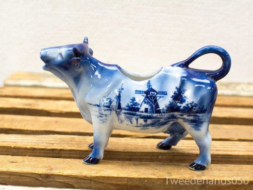 Charming Delft Blue cow creamer, handcrafted with intricate windmill designs, perfect for decor or use.