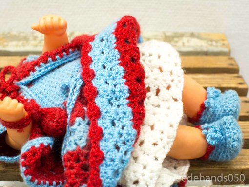 Charming vintage doll dressed in a colorful, handcrafted crocheted dress against a rustic background.
