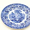 Intricate blue-and-white plate with a serene landscape, castle, and ornamental border design.