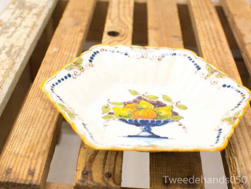 Vintage hexagonal ceramic dish with colorful fruit design on rustic wooden surface.