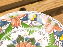 Vintage ceramic plate featuring vibrant floral patterns and elegant scalloped edges.