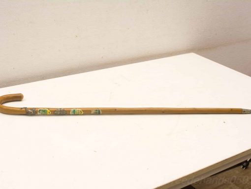 Vintage wooden cane with colorful decorative stickers, blending functionality and charm.