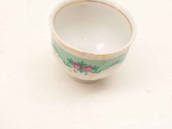 Elegant porcelain teacup with turquoise band, floral motif, and luxurious gold accents.