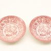 Vintage red transferware plates featuring charming pastoral scenes and scalloped rims.