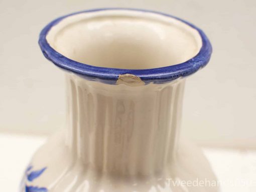Elegant ceramic vase with cobalt blue rim and floral design, showcasing unique craftsmanship.