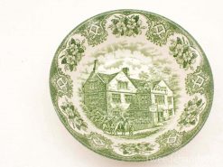 Vintage green decorative plate featuring an inn and floral designs, perfect for collection or decor.