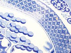 Vintage blue and white ceramic plate featuring a stylized tree and intricate decorative patterns.
