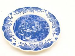 Blue and white decorative plate featuring a nostalgic gathering scene with detailed floral border.