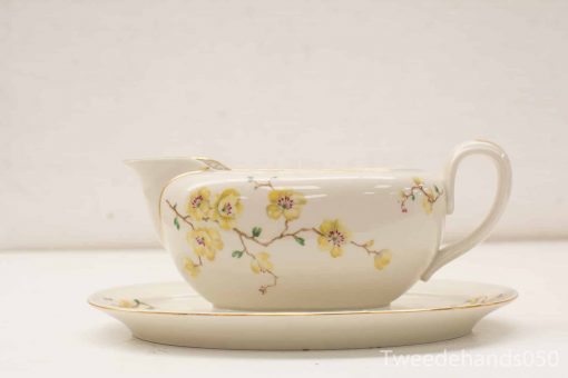 Elegant porcelain gravy boat and saucer with floral design, perfect for formal dining.