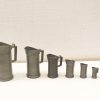 Vintage metal measuring jugs in various sizes, perfect for nostalgic kitchens and practical use.