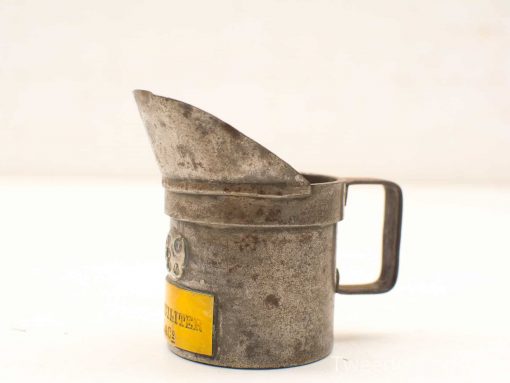 Vintage metal measuring cup with patina and yellow label, perfect for retro kitchen decor.