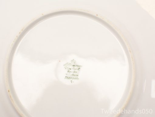 Elegant antique porcelain plate with crown emblem, showcasing exquisite craftsmanship and history.