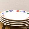 Decorative floral plates stacked on rustic wood surface, enhancing cozy dining atmospheres.
