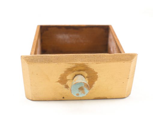Nostalgic vintage wooden drawer with yellow finish and blue knob, showcasing rustic charm and history.